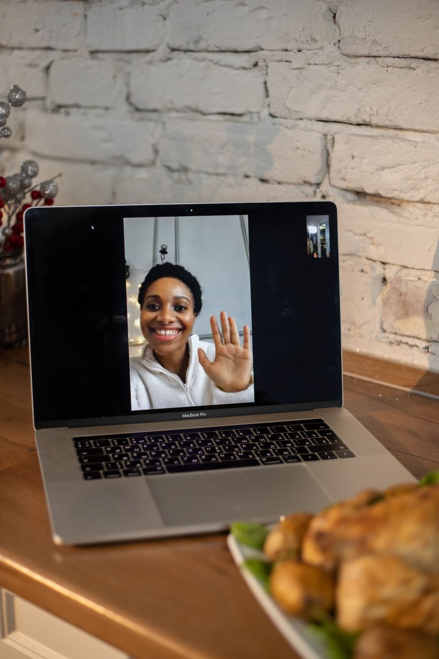A laptop on a counter with a woman waving on screen